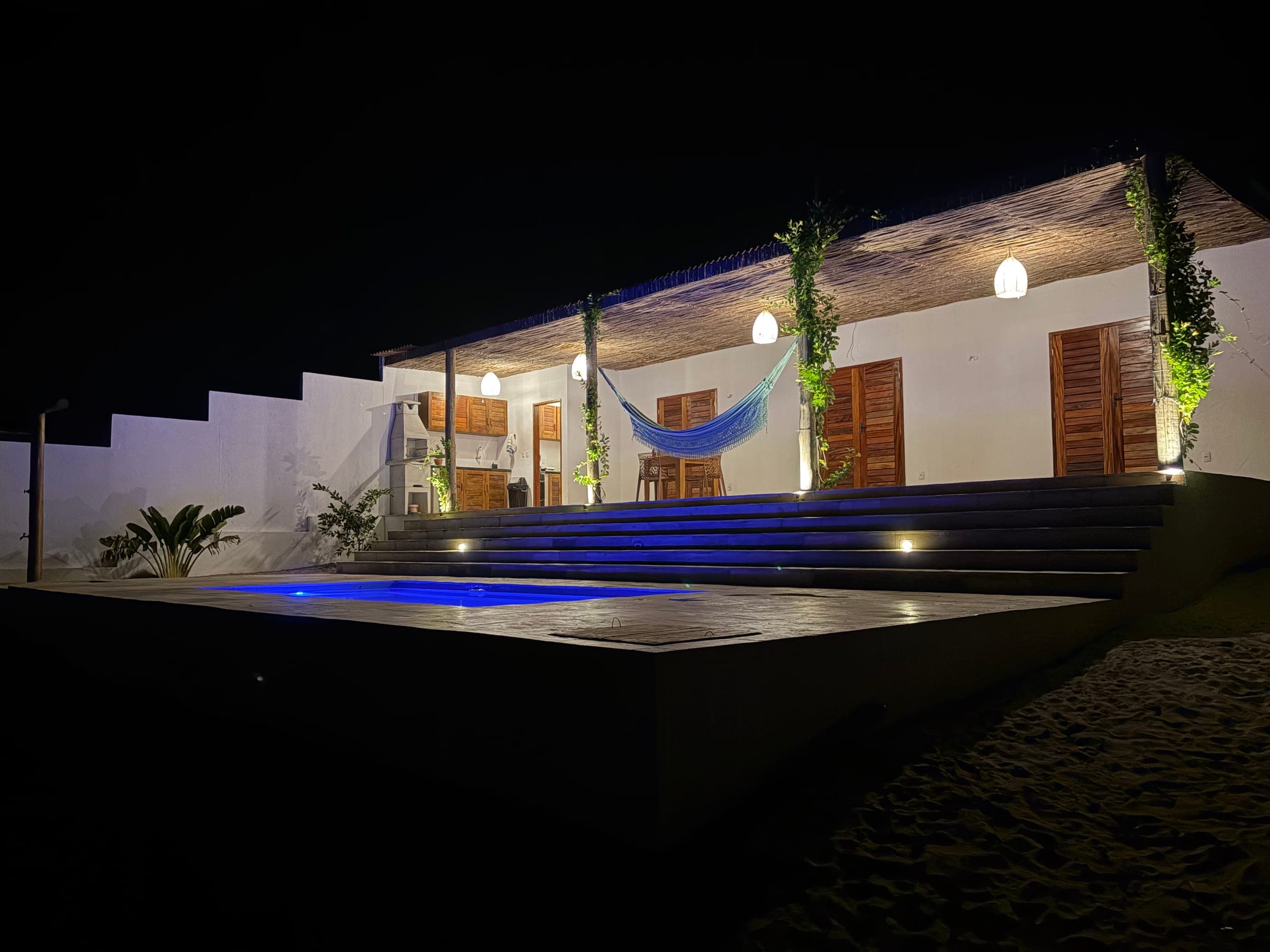 La maison et sa piscine éclairées à la nuit tombée