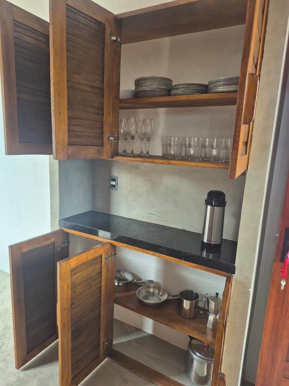 Placard ouvert : vaisselle, verres et bouteille isotherme