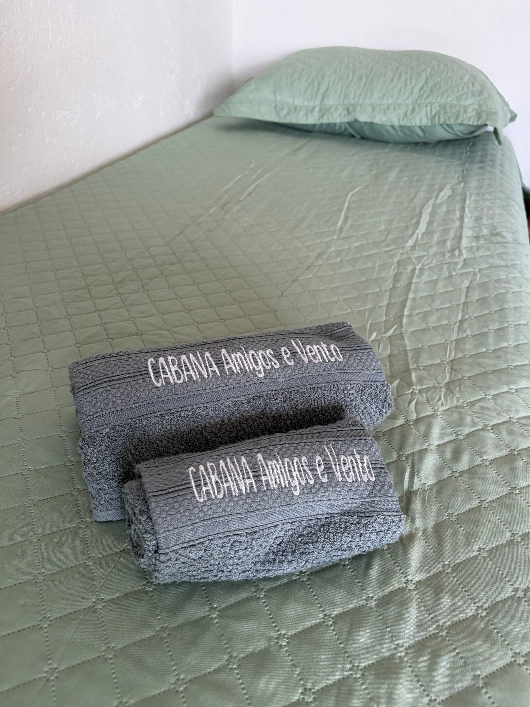 Serviettes brodées Cabana Amigos e Vento, pliées sur le lit